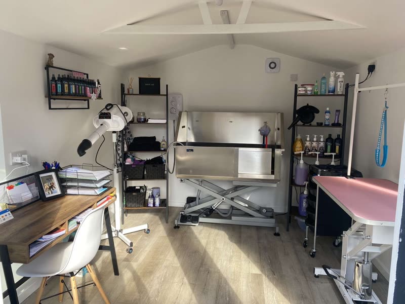 The light, pitched-roof grooming room with hydraulic table, bath and product shelving